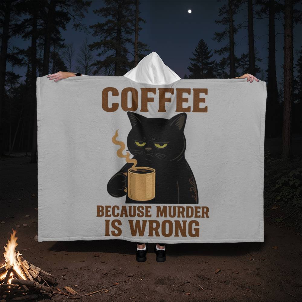 Person holding a blanket with a black cat and coffee cup design in a forest setting.