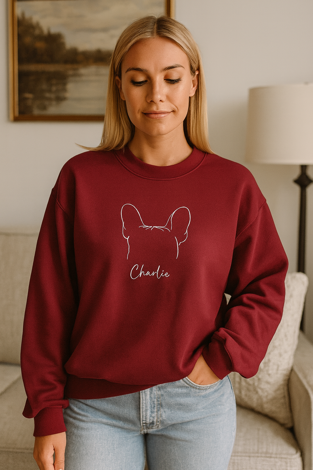 Woman wearing a maroon sweatshirt with a dog design and 'Charlie' text in a living room.