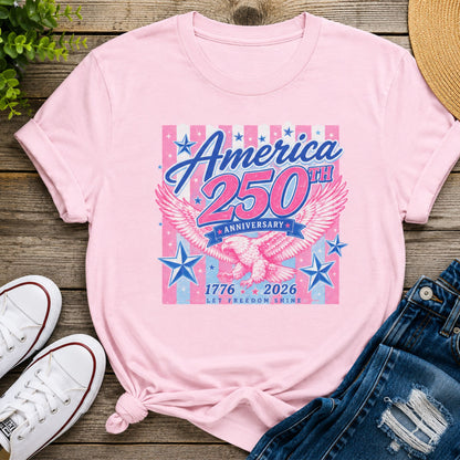 America 250th Anniversary patriotic graphic tee in light pink featuring a vintage eagle, stars, and 1776-2026 anniversary design styled with denim shorts and white sneakers.