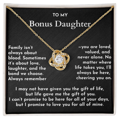 Gold necklace with a heart-shaped pendant on a black card with text for a bonus daughter.