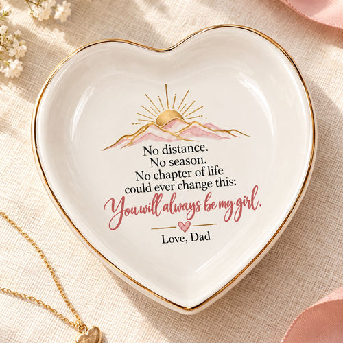 Heart-shaped white jewelry dish with gold trim and an Always My Girl message from Dad, displayed on soft ivory fabric.
 Copy alt text