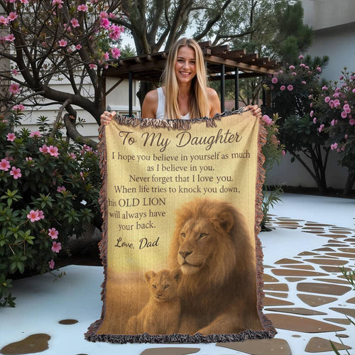 Woman holding a blanket with a lion design and text outdoors.