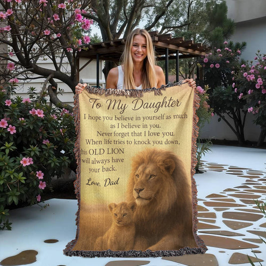 Woman holding a blanket with a lion design and text outdoors.